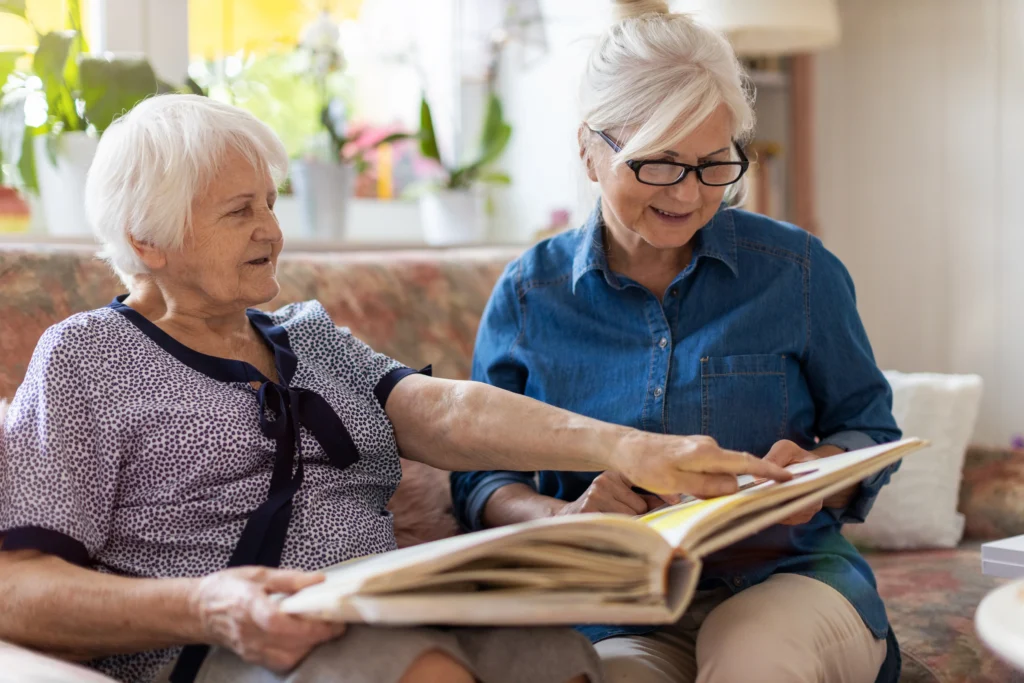Senior woman reading photo album with caregiver at Franklin Johns Creek